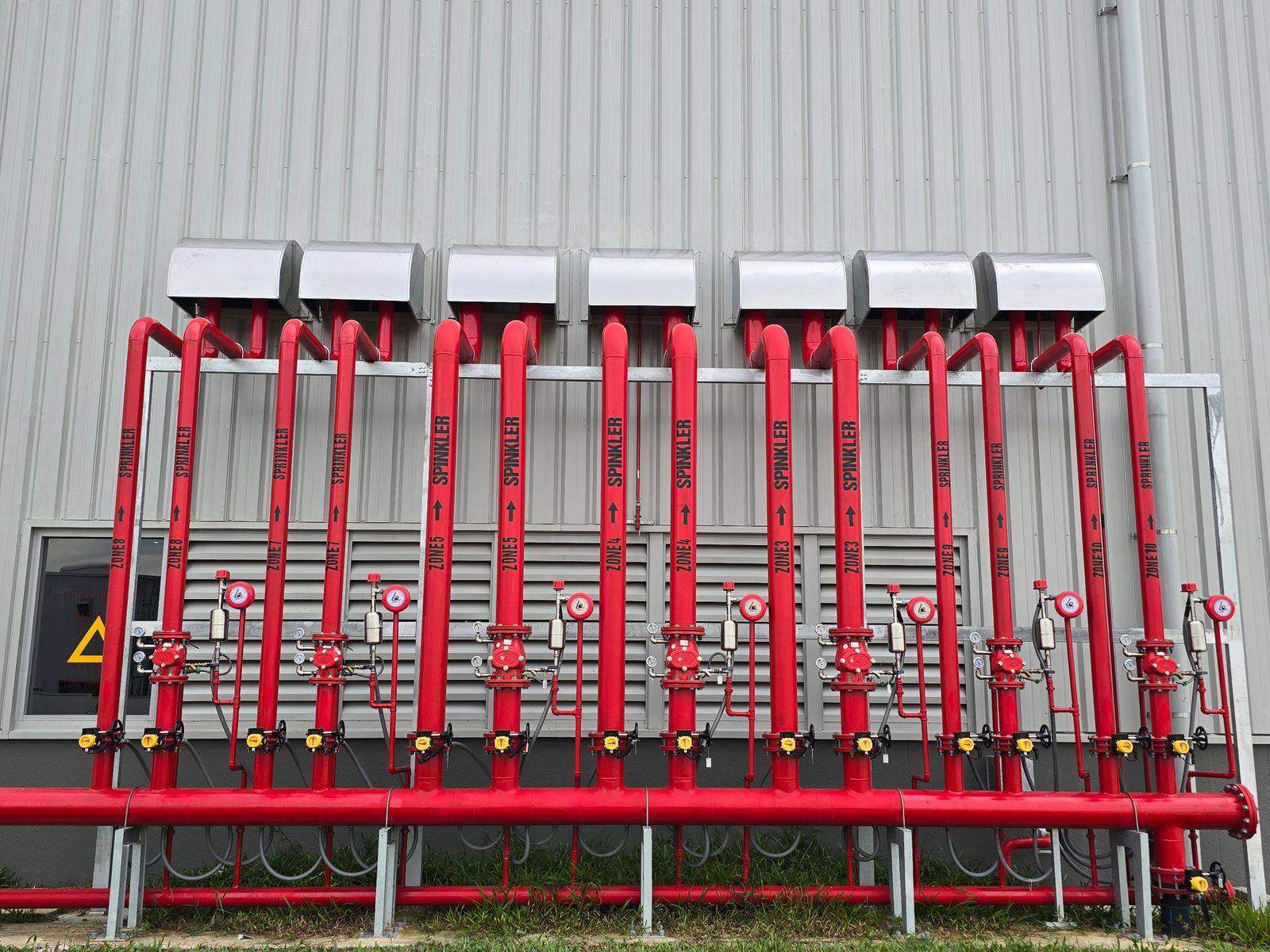 Bank of red fire sprinkler risers and zone valves at a VA campus