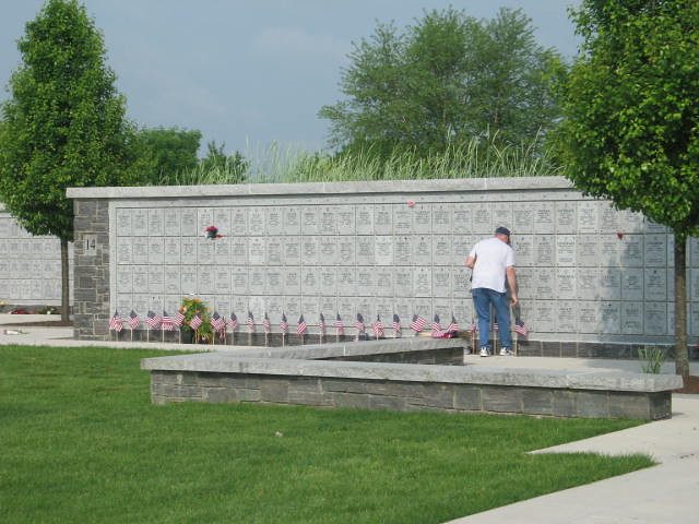 A visitor standing at the columbarium walls, with flags placed along the base